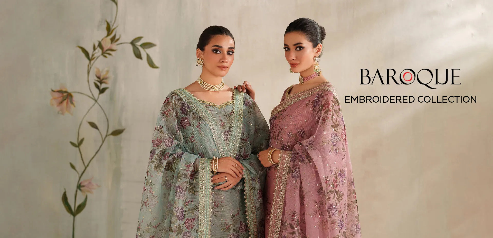 Two women modeling traditional embroidered Indian ethnic outfits in a studio setting. The left model wears a dusty pink embroidered kurta set with a matching sheer dupatta, and the right model wears a sage green embroidered kurta set with a matching sheer dupatta.1621243260e1af0c20-0